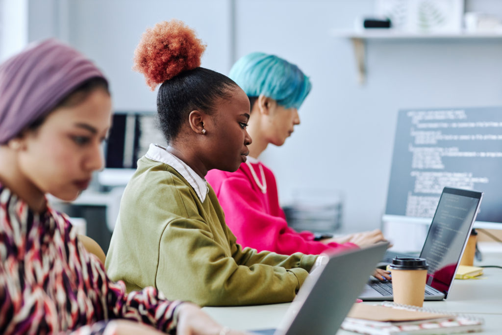 Diverse group of creative young people sitting in row working in office